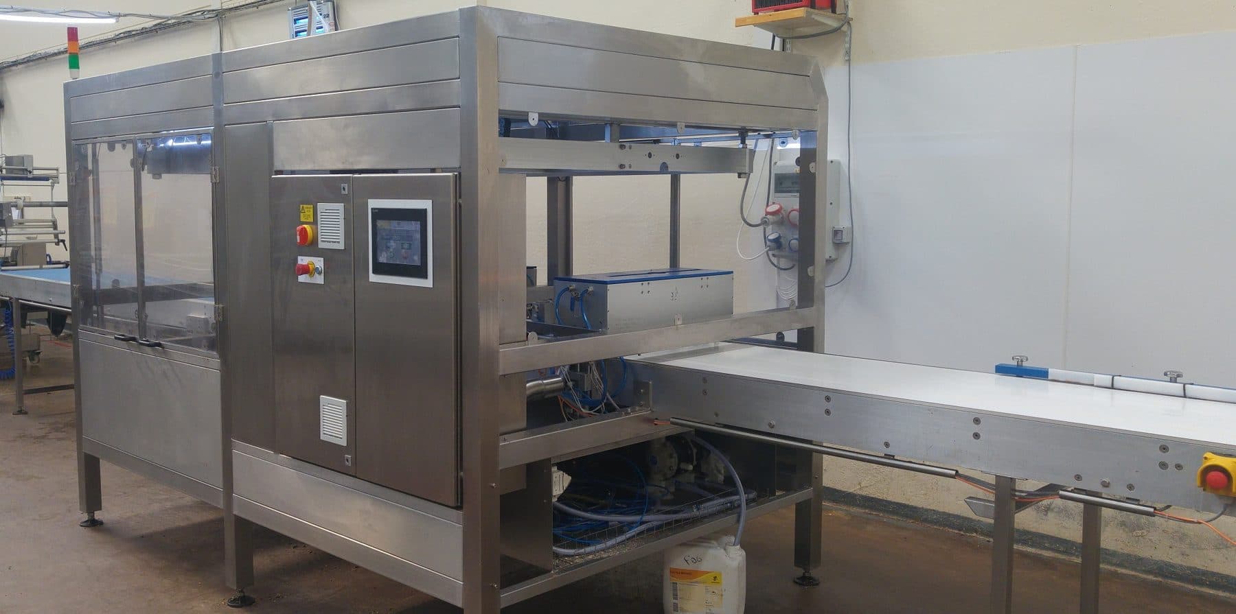 Stainless steel ultrasonic cake cutting machine with a touchscreen on its control enclosure